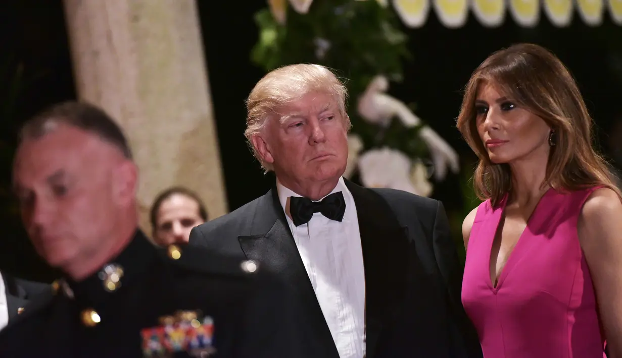 Melania Trump mendampingi Donald Trump saat menghadiri gala tahunan Palang Merah Amerika ke-60 di Mar-a-Lago, Florida, AS (4/2). First Lady Melania Trump tampil anggun dengan mengenakan gaun berwarna merah muda. (AFP/Mandel Ngan)