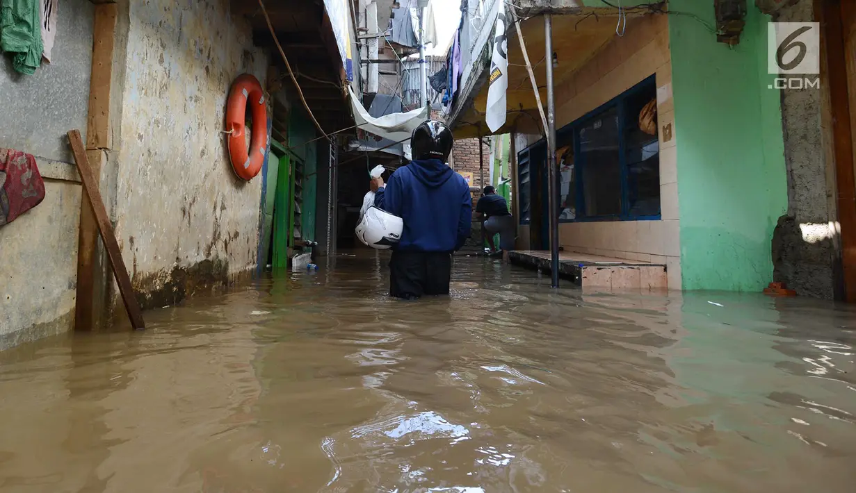 Seorang warga melintas saat banjir merendam permukiman di Kebon Pala, Jatinegara, Jakarta, Selasa (26/2/2019). Banjir setinggi 1,5 meter itu terjadi karena air Sungai Ciliwung meluap akibat air kiriman dari Bogor, Jawa Barat. (Merdeka.com/Imam Buhori)