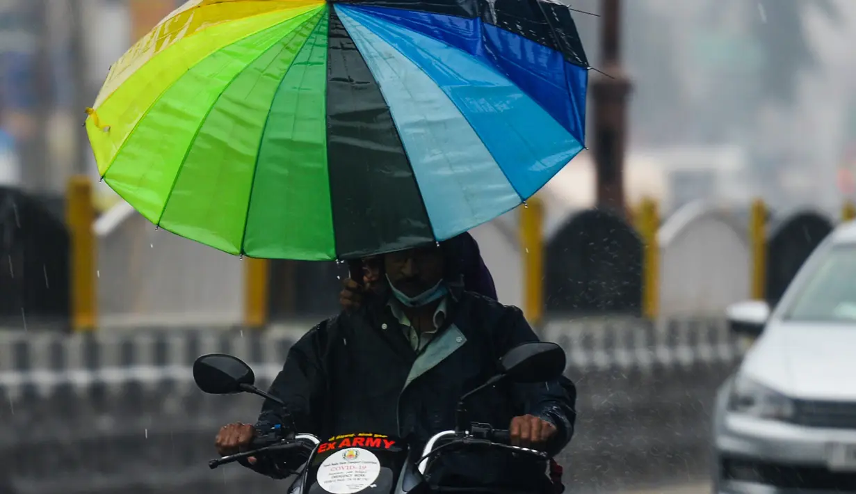 Seorang pengendara sepeda motor berkendara di sepanjang jalan di bawah hujan lebat di Chennai ketika topan Nivar mendekati pantai tenggara negara itu, (25/11/2020). (AFP/Arun Sankar)
