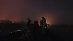 Orang-orang melihat ke gunung berapi Cumbre Vieja yang terus meletus di pulau Canary La Palma, Spanyol pada Sabtu (16/10/2021). Para pejabat mengatakan tidak ada tanda-tanda bahwa letusan gunung berapi di pulau La Palma Spanyol akan segera berakhir, satu bulan setelah dimulai. (AP Photo/Daniel Roca)