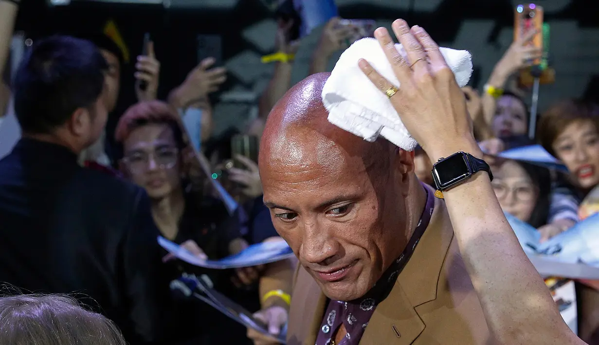 Staf menyeka keringat aktor Dwayne Johnson selama acara red carpet dalam premiere film 'Fast & Furious: Hobbs & Shaw' di Beijing, China, Senin (5/8/2019). Hobbs and Shaw menempatkan dua aktor laga papan atas, Jason Statham dan Dwayne Johnson sebagai pemeran utama. (AP Photo/Andy Wong)