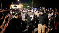 Gubernur Jawa Tengah Ganjar Pranowo dan Wali Kota Solo Gibran Rakabuming Raka mengikuti prosesi kirab pusaka malam 1 Suro yang digelar di Pura Mangkunegaran, Solo, Jumat malam (29/7).(Liputan6.com/Fajar Abrori)