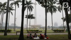 Pengunjung beristirahat sambil menikmati suasana kawasan Monas, Jakarta, Selasa (26/12/2023). (merdeka.com/Imam Buhori)