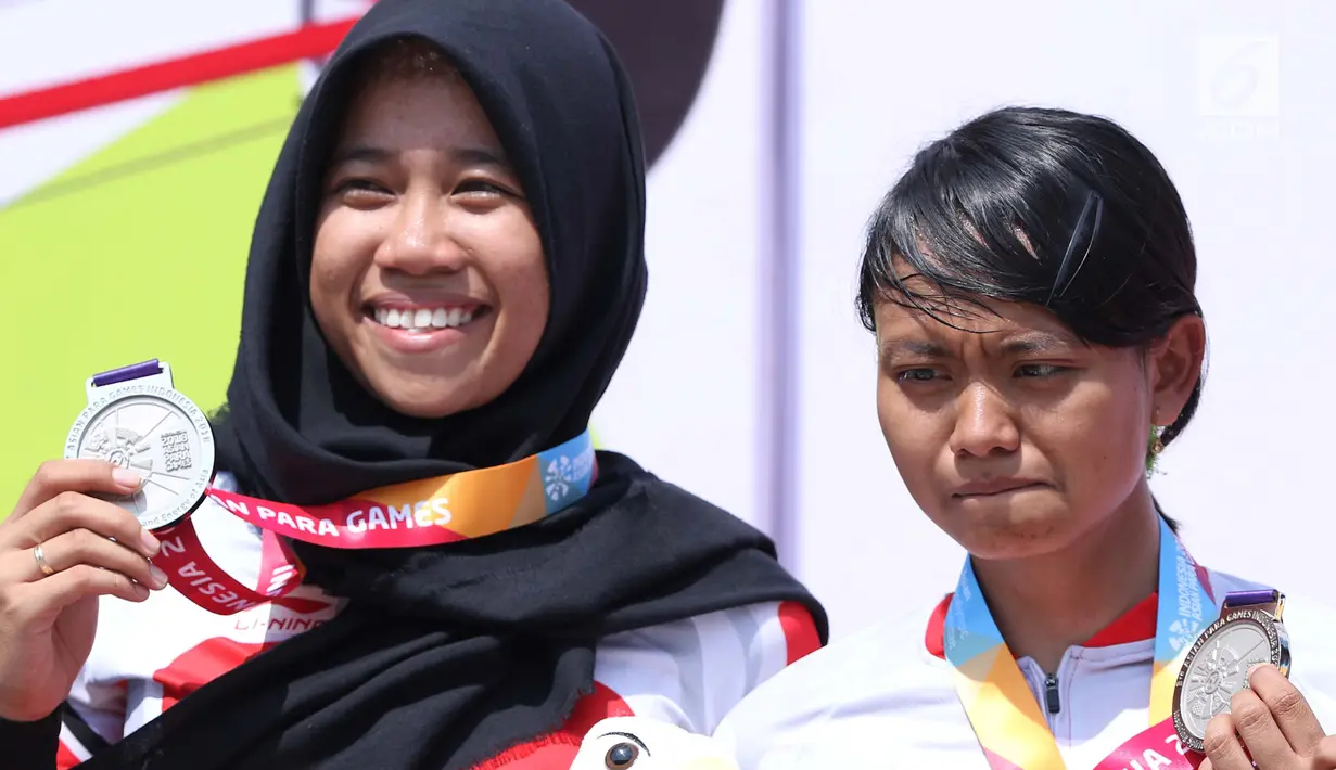 Atlet ParaCycling, Ni Mal Maghfiroh (pilot) dan Sri Sugiyanti (B) saat pengalungan medali nomor Womens B Road Race Asian Para Games 2018 di Sirkuit Sentul, Selasa (9/10). Ni Mal Maghfiroh dan Sri Sugiyanti meraih perak. (Liputan6.com/Helmi Fithriansyah)
