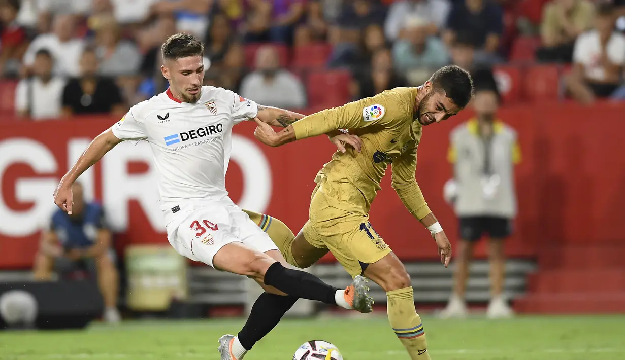 Bek Sevilla, Jose Angel Carmona berebut bola dengan bek Barcelona, Eric Garcia selama pertandingan lanjutan La Liga Spanyol di Seville, Spanyol, Sabtu (3/9/2022). Barcelona menang telak atas Sevilla 3-0. (AP Photo/Jose Breton)