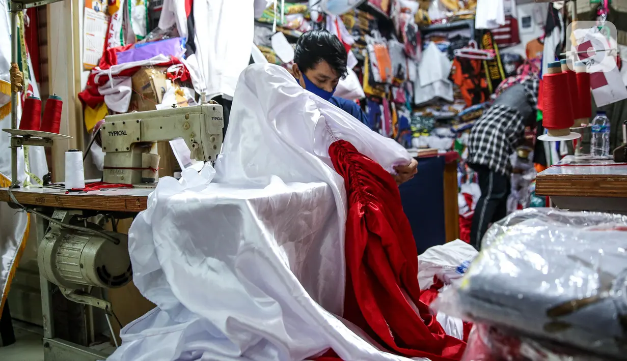 Pekerja menjahit bendera merah putih di kiosnya, kawasan Pasar Senen, Jakarta, Rabu (5/8/2020). Menjelang peringatan HUT ke-75 Kemerdekaan RI, sejumlah pedagang mengaku penjualan pernak-pernik bendera merah putih menurun 50 persen dibanding tahun lalu akibat COVID-19. (Liputan6.com/Faizal Fanani)