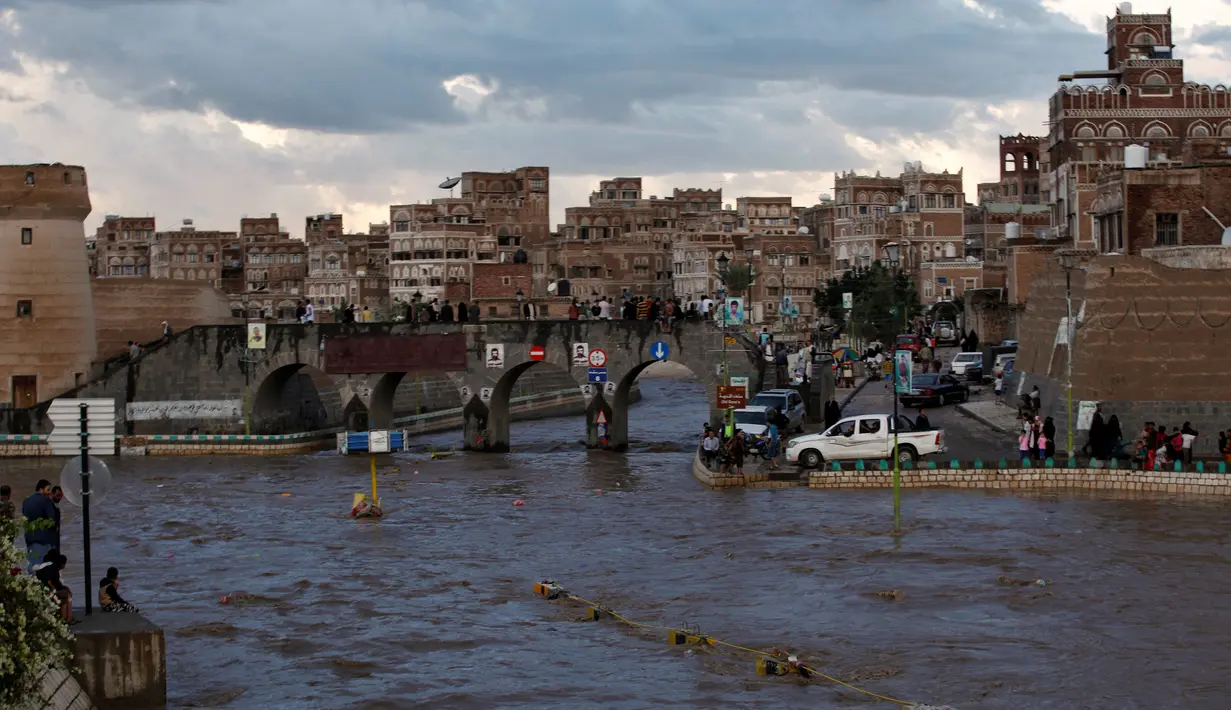 Sejumlah warga melihat jalanan yang terendam banjir di Sanaa, Yaman, Selasa (2/8). Hujan lebat yang mengguyur Sanaa membuat salah satu ruas jalan di kota itu berubah seakan menjadi sungai. (REUTERS / Khaled Abdullah)