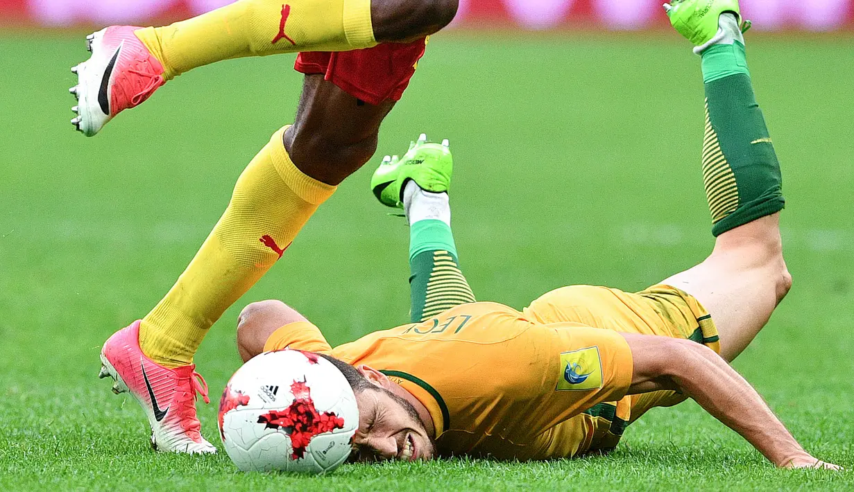 Pemain Australia, Mathew Leckie terjatuh saat berduel dengan pemain Kamerun pada laga grup B Piala Konfederasi 2017 di Saint Petersburg Stadium, (22/6/2017). (AFP/Mladen Antonov)