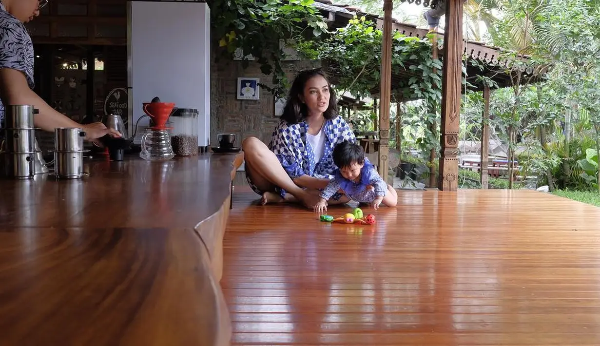 Bermain dengan Salma pun Atiqah tetap memesona. Seperti yang terlihat di foto ini, ia mengenakan short pants dan atasan bermotif kotak-kotak. (Instagram/atiqahhasiholan)