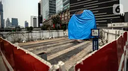 Suasana Proyek Pembangunan tugu sepeda di Jalan Jenderal Sudirman, Jakarta, Rabu (30/3/2022). Tugu yang dulu sempat boming dan digembar-gemborkan kini terlihat terhenti pengerjaannya dan hanya ditutup terpal. (Liputa6.com/Johan Tallo)