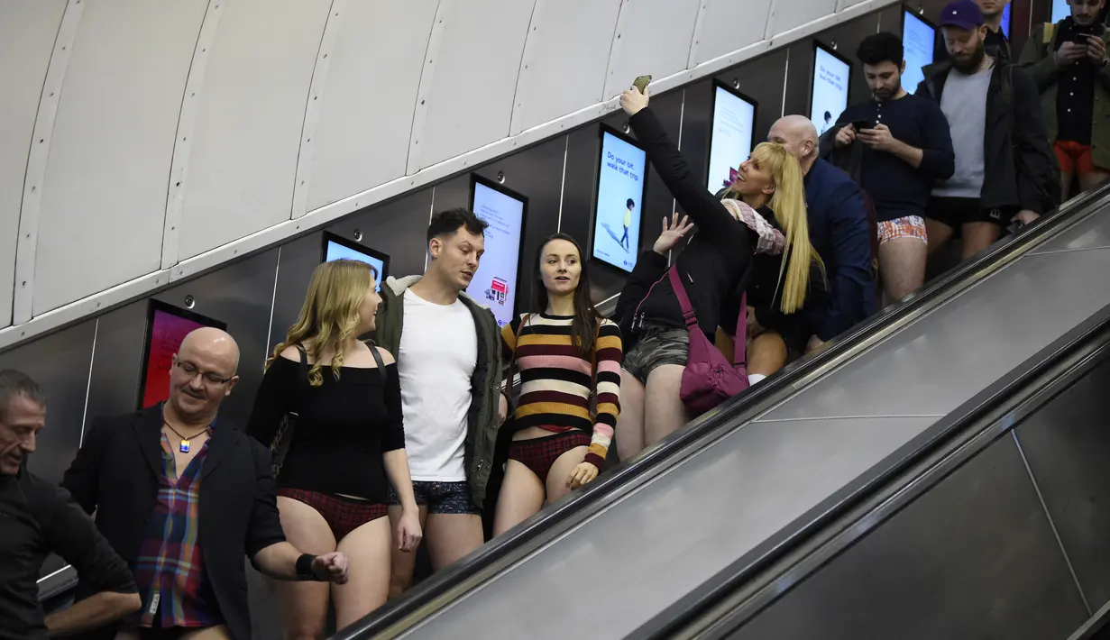 Orang-orang menggunakan eskalator saat ambil bagian dalam 'No Trousers On The Tube Day' atau No Pants Subway Ride di London Underground,  pusat Kota London, Minggu (12/1/2020). New York menjadi kota pertama yang menghajat acara naik kereta tanpa celana ini sejak tahun 2002. (DANIEL LEAL-OLIVAS/AFP)
