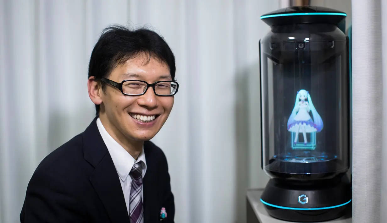 Akihiko Kondo asal Jepang berpose di sebelah hologram aktris virtual, Hatsune Miku seminggu setelah pernikahan mereka di Tokyo, 10 November 2018. Pengalaman traumatis yang terjadi 10 tahun lalu membuat Kondo trauma pada wanita. (Behrouz MEHRI/AFP)