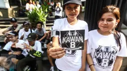 Dua pemudi menunjukkan stiker kawan8 saat Car Free Day di Senayan, Jakarta, Minggu (24/7). Kawan8 merupakan relawan netizen untuk membela 8 orang korban Jakarta International School yang mencuat pada tahun 2014. (Liputan6.com/Fery Pradolo)