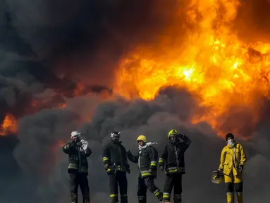 Petugas pemadam kebakaran saat berusaha memadamkan api di salah satu tangki minyak yang terbakar di pelabuhan Es Sider, Libya, (6.1).  Diduga penyebab kebakaran adalah serangan yang dilakukan oleh kelompok militan. (REUTERS / Stringer)