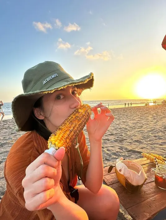 Ingin menikmati keindahan sunset di pantai sambil makan jagung bisa kamu lakukan. Untuk pakaian kamu bisa mrmilih warna cerah yang dipadukan dengan topi sebagai aksesoris