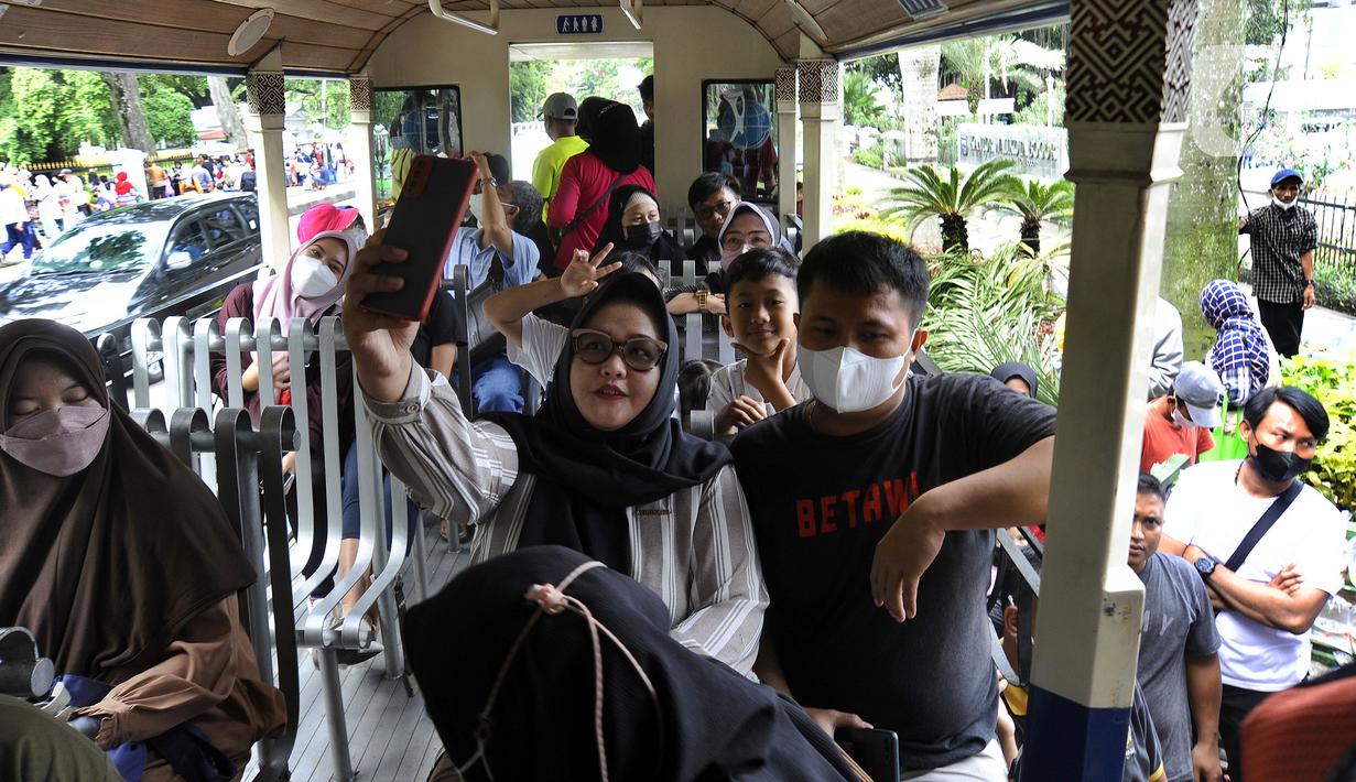 Warga berswafoto dalam bus wisata Uncal di depan Balai Kota Bogor, Bogor, Jawa Barat, Minggu (29/5/2022). Bus wisata gratis yang disediakan untuk mengelilingi kawasan Kebun Raya Bogor setiap hari Sabtu dan Minggu ini mulai beroperasi kembali pascapandemi. (merdeka.com/Arie Basuki)