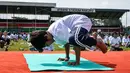 Seorang anak lelaki melakukan gerakan yoga saat mengikuti yoga massal di Stadion Afraha, Nakuru, Kenya (15/6/2019). Hari Yoga Internasional, yang setiap tahun dirayakan pada 21 Juni, pertama kali diusulkan Perdana Menteri India Narendra Modi pada 2014 ke Majelis Umum PBB. (AFP Photo/Suleiman Mbatiah