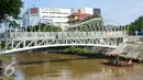 Jembatan penyeberangan dibangun di atas Sungai Ciliwung, Jakarta, Senin (4/4). Jembatan itu untuk mempermudah warga menyeberang dan rencaanya akan siap digunakan pada 6 April mendatang. (Liputan6.com/Yoppy Renato)