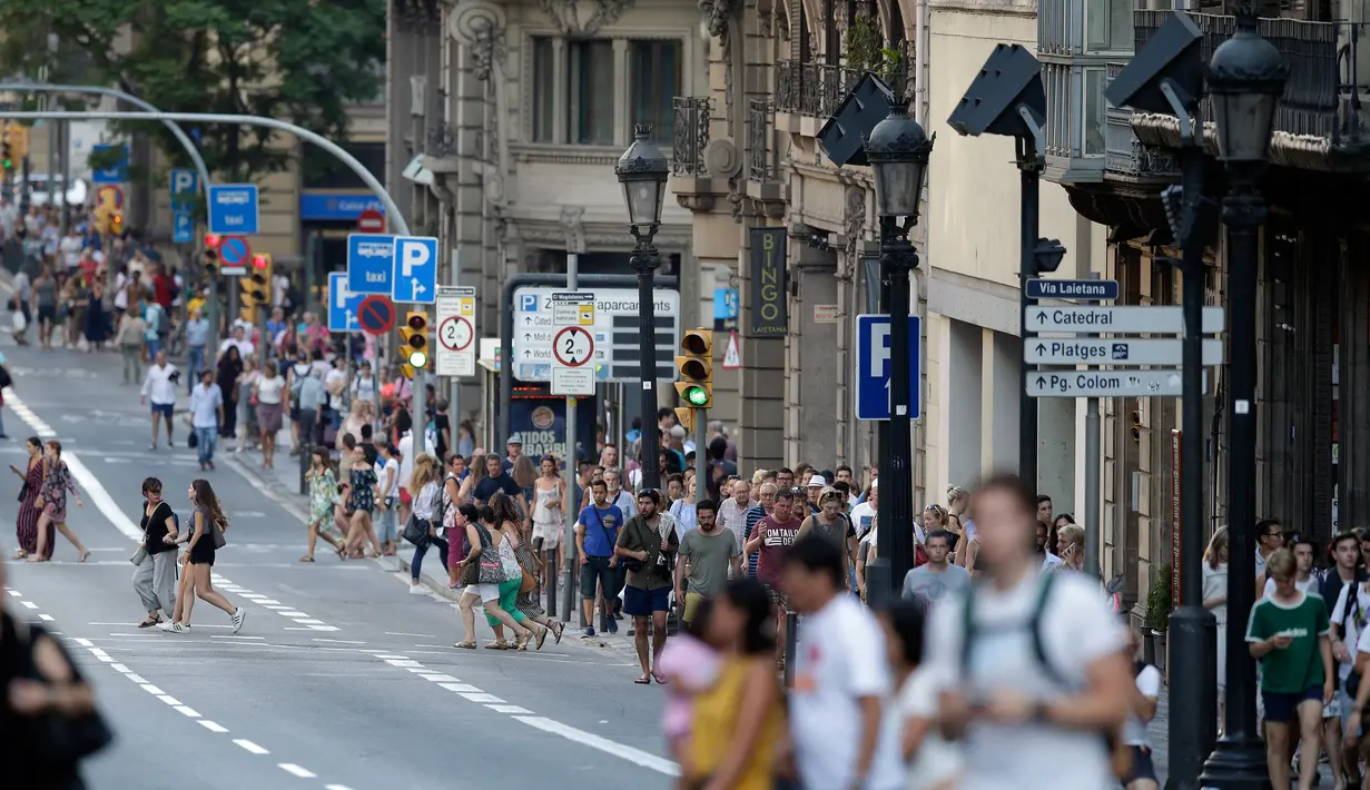 Warga dan turis berjalan pasca mobil van menabrak kerumunan orang  di Jalanan Las Ramblas, Barcelona, Spanyol (17/8). Saksi mata mengatakan, sebelum menabrak kerumunan, van melaju secara zig zag dengan kecepatan tinggi. (AP Photo/Manu Fernandez)