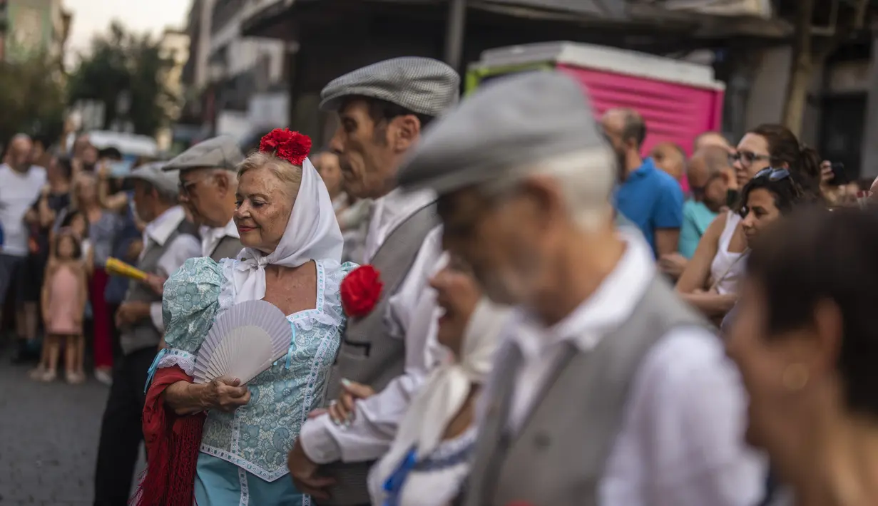 Orang-orang yang mengenakan pakaian tradisional 'chulapo' menari selama perayaan San Cayetano, santo pelindung tenaga kerja dan roti, di lingkungan Lavapies di Madrid, Spanyol, Sabtu (6/8/2022). Festival San Cayetano menandai awal dari serangkaian festival populer di Madrid. (AP Photo/Manu Fernandez)