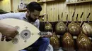 Seorang pengrajin, Ali Khalifeh mencoba alat musik Oud setelah selesai di buat di sebuah rumah produksi di Damaskus, Suriah (17/7). Oud adalah alat musik yang mirip gitar yang berasal dari Afrika Utara dan Timur Tengah. (AFP Photo/Louai Beshara)