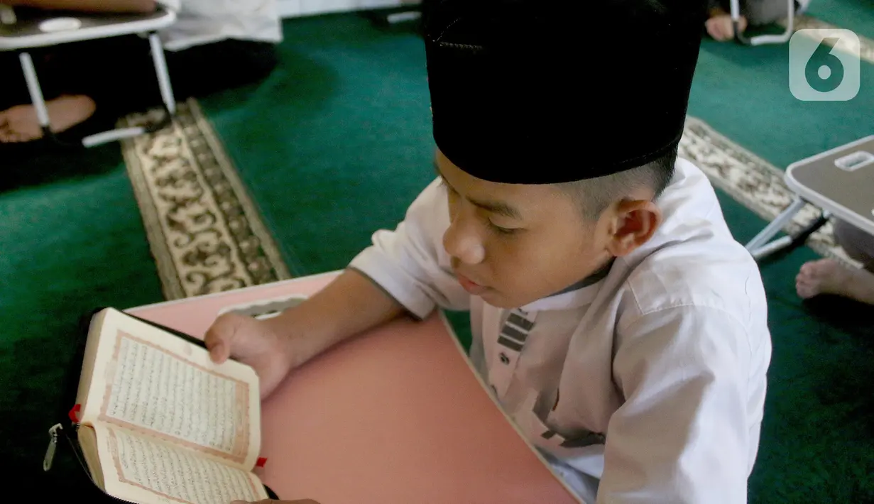 Santri yang masih berusia belasan tahun membaca Al Quran bersama-sama (tadarus) dalam rangka mengkhatamkan Qur'an dengan menerapkan jaga jarak pada Masjid Daarul Qu'ran  Pesantren Al Kautsar, Cibinong, Bogor, Jawa Barat, Minggu (10/04/2022). (merdeka.com/Arie Basuki)