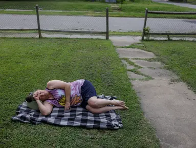 Dawn Borchert tidur di halaman depan rumahnya di sebuah lingkungan dekat 11th Street dan Lewis Ave, di Tulsa, Oklahoma, Selasa (20/6/2023). Borchert tidak memiliki listrik sejak badai akhir pekan dan tidur di tenda semalaman, tetapi pindah ke luar untuk menyejukkan diri pada pagi hari. (Mike Simons/Tulsa World via AP)