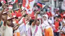 Siswa-siswi SD membawa bendera negara peserta Asian Games 2018 untuk menyambut Kirab Obor di kawasan Jati Padang, Pasar Minggu, Rabu (15/8). Mereka memenuhi jalanan untuk menyaksikan langsung Pawai Obor Asian Games 2018. (Liputan6.com/Faizal Fanani)