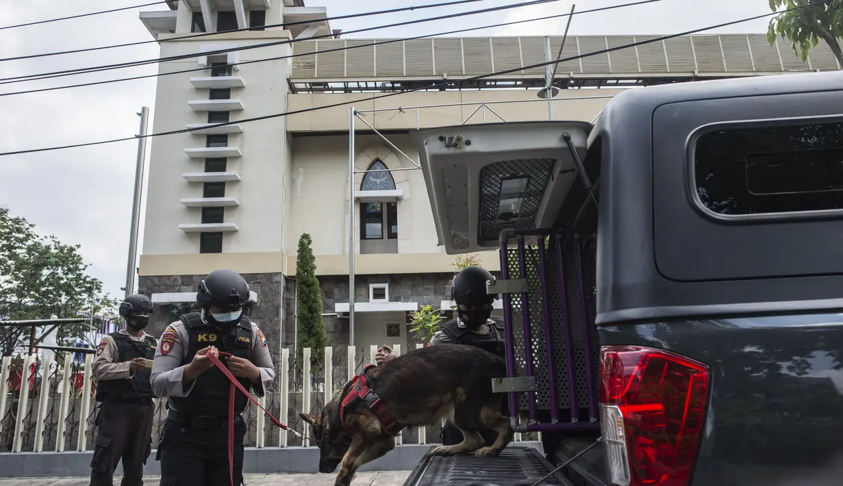 Polisi membawa anjing pelacak untuk pemeriksaan keamanan di sebuah gereja di Surabaya menjelang Paskah setelah bom bunuh diri di katedral Makassar, Rabu (31/3/2021). Kegiatan tersebut merupakan upaya peningkatan pengamanan tempat ibadah, khususnya gereja di kota pahlawan. (Juni Kriswanto/AFP)