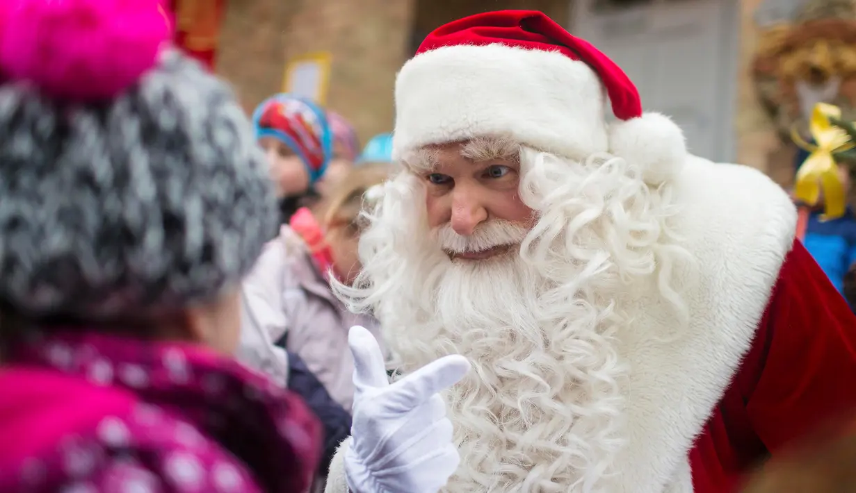 Seorang pria berpakaian Santa Claus berbicara dengan seorang anak di kantor pos desa Himmelpfort, Jerman, (10/11/2015). Lebih dari ribuan surat telah diterima oleh Deutsche Post. (REUTERS/Hannibal Hanschke)