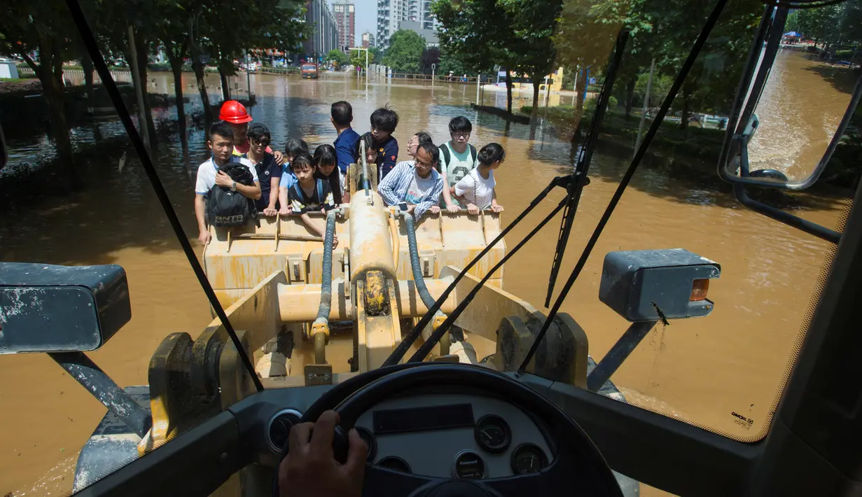 Pekerja mengendarai ekskavator saat membawa para warga menuju kantor di Wuhan, provinsi Hubei, (8/7). Banjir hebat yang belum juga surut membuat warga kesulitan menjalani aktivitasnya. (REUTERS/Stringer)