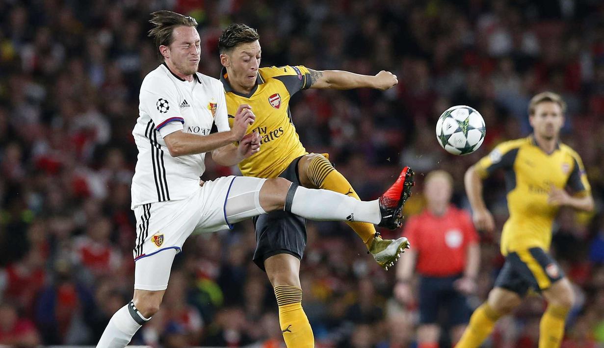 Pemain Basel, Luca Zuffi (kiri) berusaha menghadang sepakan Mesut Ozil pada laga grup A Liga Champions di Emirates stadium, London, Kamis (29/9/2016)dini hari WIB. (AP/Alastair Grant)