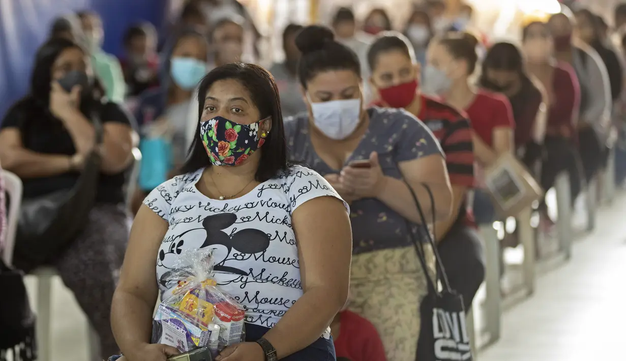 Sejumlah wanita duduk setelah menerima sumbangan pembalut dan perlengkapan kebersihan perempuan lainnya di tengah pandemi COVID-19 di favela Paraisopolis, di Sao Paulo, Brasil (24/5/2021). Sumbangan ini disediakan oleh LSM lokal "G10 Favelas". (AP Photo/Andre Penner)