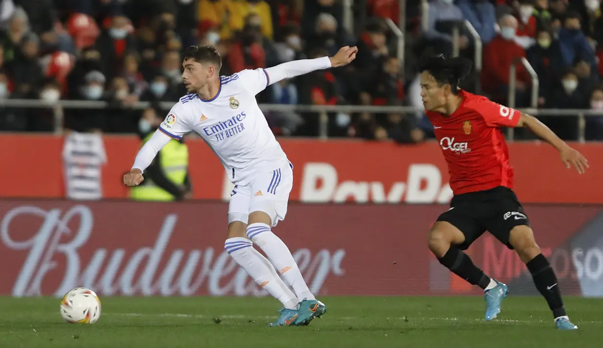 Gelandang Real Madrid, Federico Valverde mengontrol bola dari kawalan gelandang Mallorca, Takefusa Kubo pada pertandingan lanjutan La Liga Spanyol di Palma de Mallorca, Spanyol, Selasa (15/3/2022). Madrid menang telak atas Mallorca 3-0. (AP Photo/Francisco Ubilla)