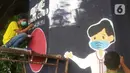 Mahasiswa melukis mural bertemakan sosialisasi pencegahan Covid-19 di kolong jalan tol dalam kota, Kebun Nanas, Jakarta, Jumat (4/12/2020). Kegiatan sekitar 90 tiang kolong tol sepanjang jalan MT Haryono ini difasilitasi Satgas Covid-19. (merdeka.com/Arie Basuki)
