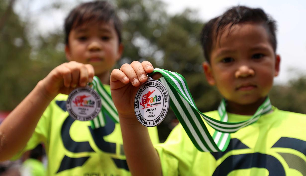 Peserta menunjungan medali usai bertanding dalam kejuaraan Invitasi Sepatu Roda DKI Jakarta di Senayan, Jakarta, Minggu (8/11/2015). Kejuaraan ini diikuti sekitar 39 klub seluruh Indonesia. (Bola.com/Nicklas Hanoatubun).