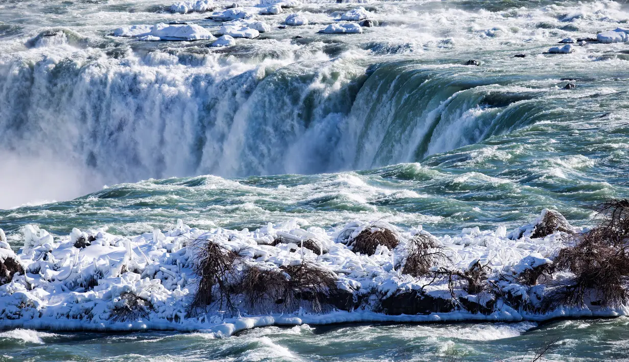 Es dan air mengalir di tepi Horseshoe Falls dari Air Terjun Niagara di Ontario, Kamis (31/1). Saat AS dilanda suhu yang lebih dingin dari Antartika, temperatur di Kanada juga menurun menjadi minus 18 derajat Celcius (Tara Walton/The Canadian Press via AP)