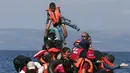Seorang anak diangkat oleh salah satu pengungsi Suriah saat perahu karet yang mereka tumpangi bocor sekitar 100 m sebelum mencapai pulau Lesbon, Yunani, Minggu (13/09/2015). (REUTERS/Alkis Konstantinidis)