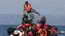 Seorang anak diangkat oleh salah satu pengungsi Suriah saat perahu karet yang mereka tumpangi bocor sekitar 100 m sebelum mencapai pulau Lesbon, Yunani, Minggu (13/09/2015). (REUTERS/Alkis Konstantinidis)