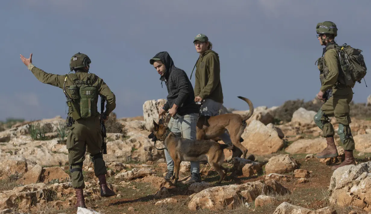 Pemukim Yahudi menggunakan anjing saat bentrok dengan pengunjuk rasa Palestina di Desa Mughayer, Ramallah, Tepi Barat, Jumat (18/12/2020). Pengunjuk rasa Palestina yang menggunakan ketapel terlibat bentrok dengan pemukim Yahudi yang menggunakan anjing. (AP Photo/Nasser Nasser)