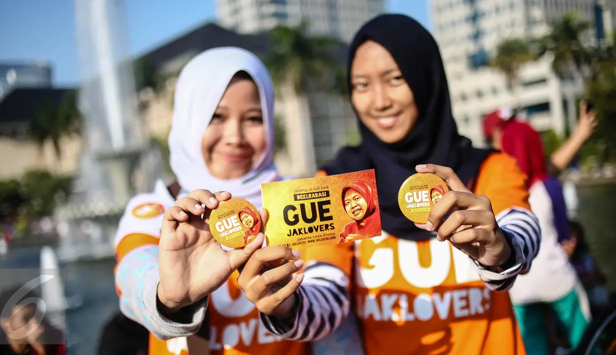 Dua anak muda dari Jaklovers menunjukkan pin saat aksi simpatik mendukung Wali Kota Surabaya Tri Rismaharini maju sebagai calon gubernur (cagub) pada Pilkada DKI 2017, di Bundaran Patung Kuda, Jakarta , Minggu (31/7). (Liputan6.com/Faizal Fanani)