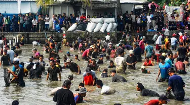 Ratusan warga menangkap ikan dengan tangan tangan kosong saat kegiatan Ngubek Empang di Jalan Abdul Ghani Raya, Kelurahan Kalibaru, Kecamatan Cilodong. Depok, Jawa Barat, Kamis (16/5/2024). (merdeka.com/Arie Basuki)