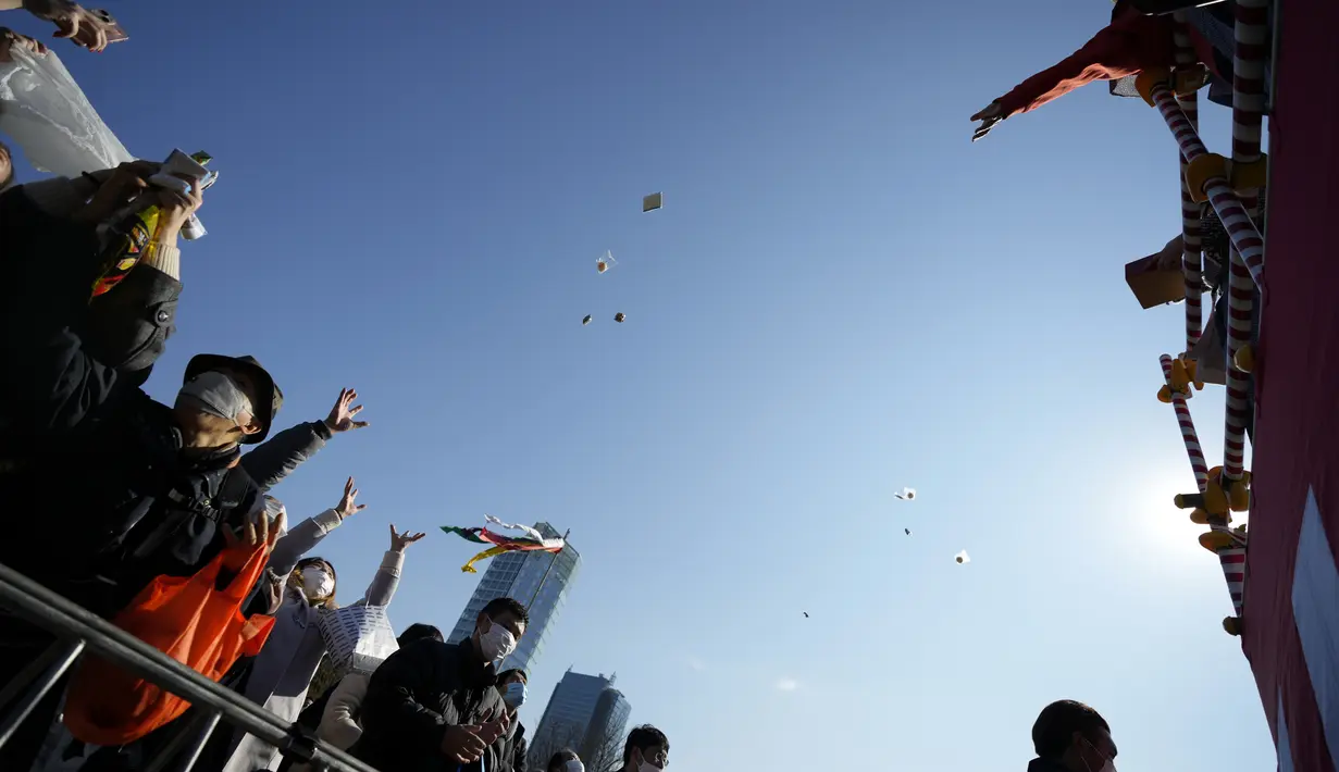 Orang-orang mencoba menangkap kacang keberuntungan yang disebarkan pada "Mame-maki," upacara pelemparan kacang di kuil Buddha Zojoji di Tokyo, 3 Februari 2022. Ritual yang diyakini membawa keberuntungan dan mengusir kejahatan dilakukan setiap tahun untuk menandai awal musim semi. (AP/Eugene Hoshiko)