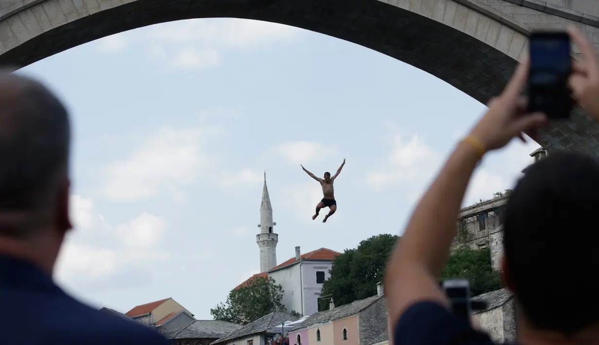 Seorang peserta melompat dari Jembatan Old Mostar pada kompetisi menyelam tradisional ke-452 di Mostar, Bosnia, 29 Juli 2018. Ini merupakan kompetisi selam tahunan yang menjadi salah satu daya tarik Bosnia dan berlangsung sejak abad ke 17. (AP/Amel Emric)