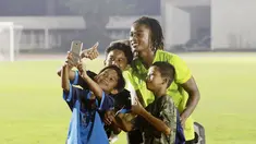 Fans cilik foto bersama dengan pemain Timnas  Indonesia U-19, Ronaldo Kwateh, usai melakukan latihan jelang Piala AFF U-19 2022 di Stadion Madya, Jakarta, Selasa (21/6/2022). (Bola.com/M Iqbal Ichsan)