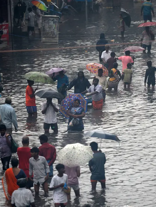 Orang-orang mengarungi jalan yang banjir setelah hujan lebat di Chennai, India (8/11/2021). Departemen Meteorologi India (IMD) memperkirakan lebih banyak curah hujan dalam beberapa hari mendatang. (AFP/Arun Sankar)
