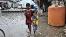 Dua orang anak melintasi banjir rob di permukiman Muara Angke, Jakarta, Selasa (22/1). Banjir air laut pasang atau Rob yang kembali melanda kawasan itu sejak 6 hari lalu membuat aktivitas warga sekitar terganggu. (Merdeka.com/Iqbal S. Nugroho)