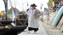 Seorang mengenakan kostum menarik perahu untuk bersandar saat Festival Loire di Orleans, Prancis (24/9). Dalam festival ini peserta mengenakan pakaian bergaya abad pertengahan. (AFP Photo/Guillaume Souvant)