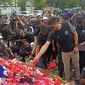 Kiper Arema FC, Adilson Maringa, menamburkan bunga di depan monumen patung Singa Tegar yang jadi ikon Stadion Kanjuruhan, sebagai tanda berduka cita atas meninggalnya ratusan Aremania setelah Tragedi Kanjuruhan, Sabtu (1/10/2022). (Bola.com/Iwan Setiawan)