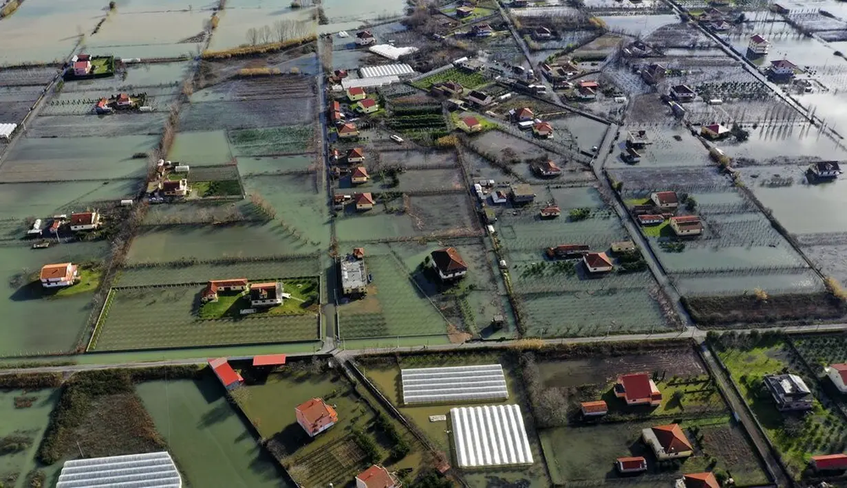 Air hujan membanjiri Desa Obot, sekitar 100 kilometer (60 mil) barat laut Tirana, Albania, Senin (11/1/2021). Pihak berwenang telah mengevakuasi banyak warga menyusul banjir yang merendam ribuan hektare (acre) kawasan di Albania. (AP Photo/Hektor Pustina)